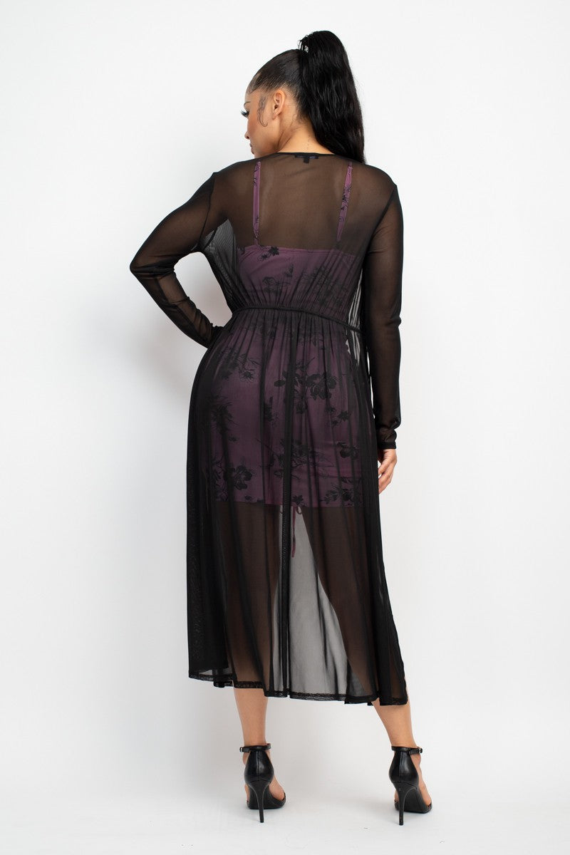 Woman wearing a sheer black duster with a dress with floral patterns on a white background