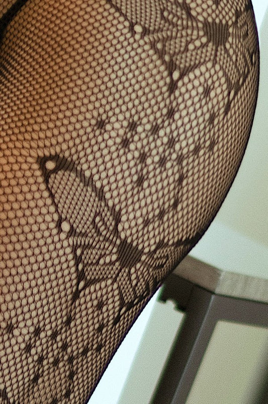 Close-up of black fishnet stockings with a pattern on a white background