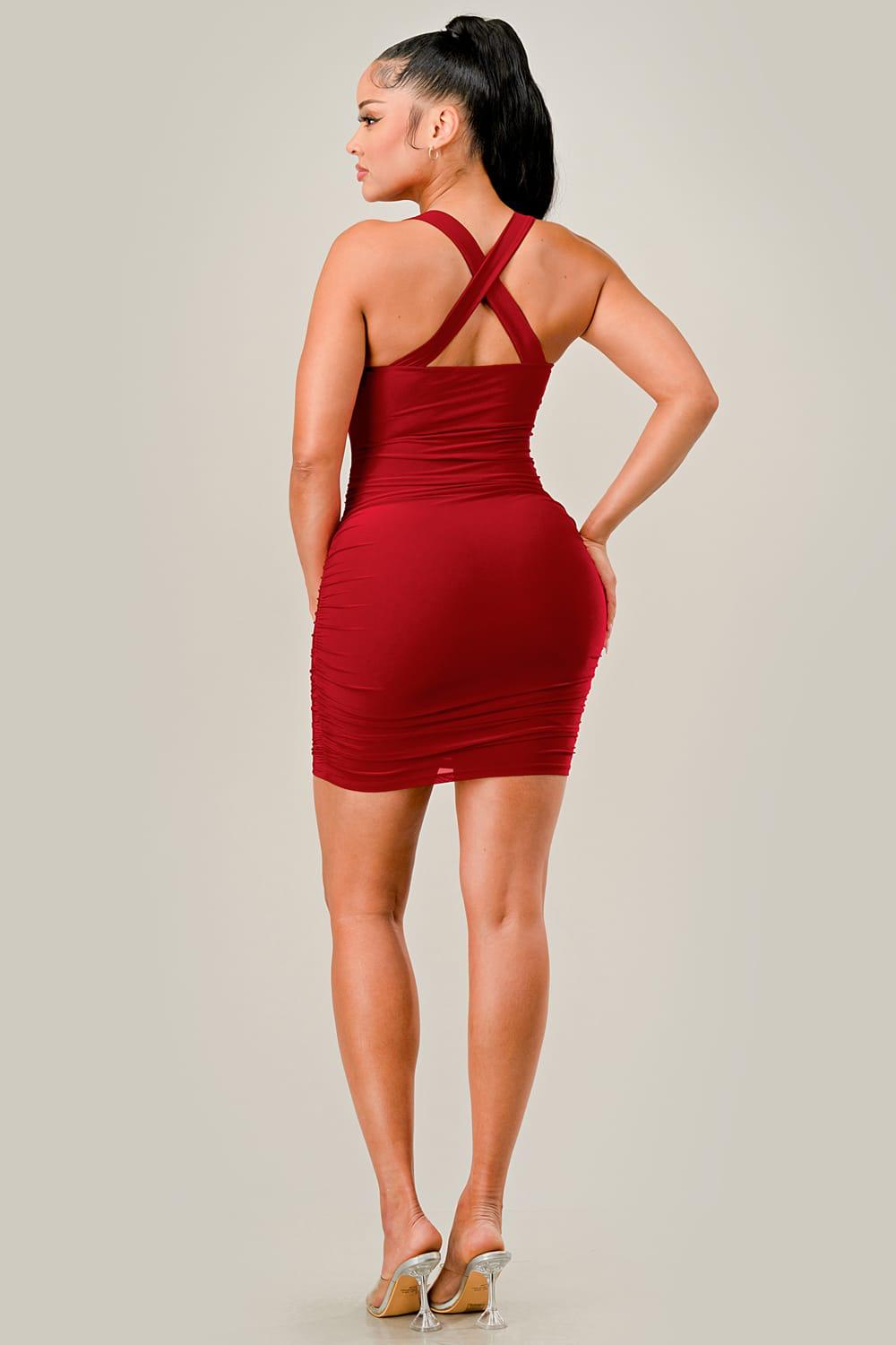 Woman wearing a red dress with crossed straps on a plain background