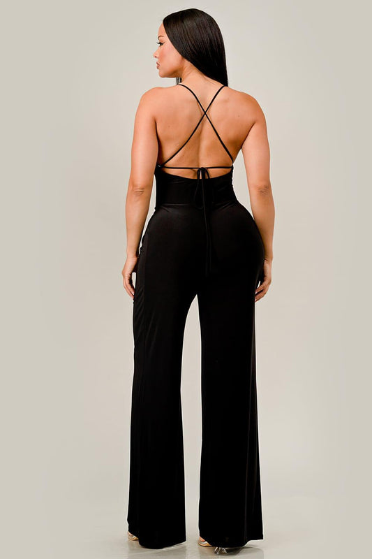 Woman wearing a black jumpsuit with thin straps on a light gray background