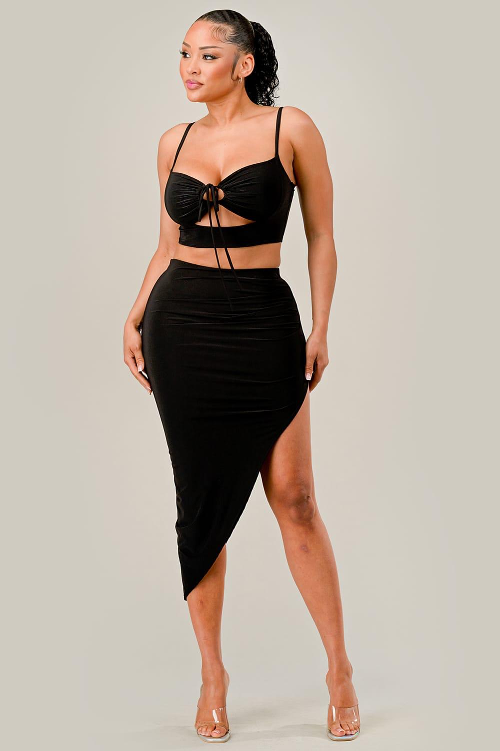 Woman wearing a black two-piece outfit with a top and skirt on a plain background