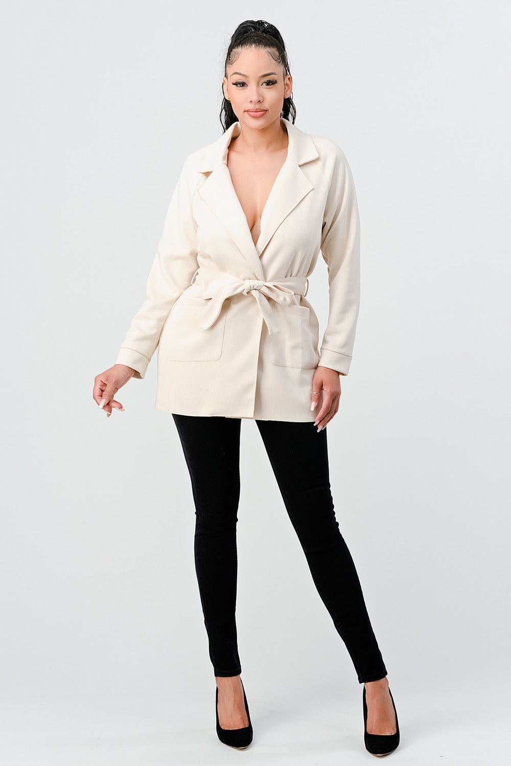 Woman wearing a cream blazer over a black top on a white background