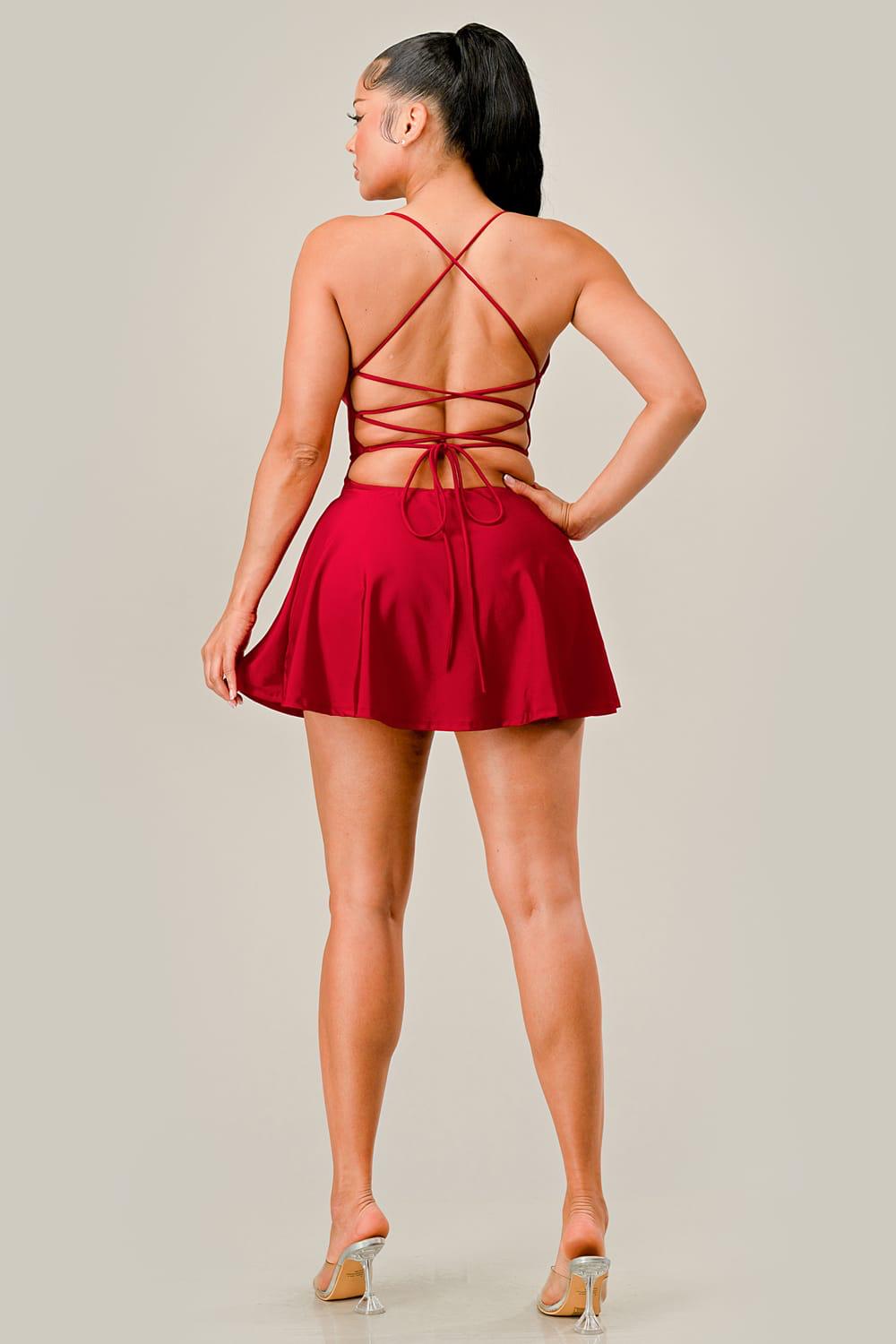 Woman wearing a red dress with a strappy back on a plain background