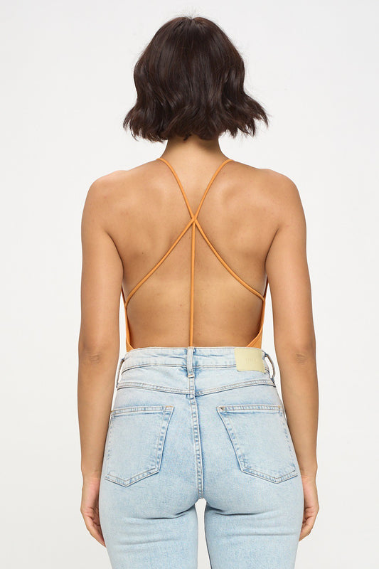 Person wearing a strappy top and light blue jeans on a white background