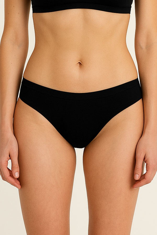 Person wearing black underwear on a beige background