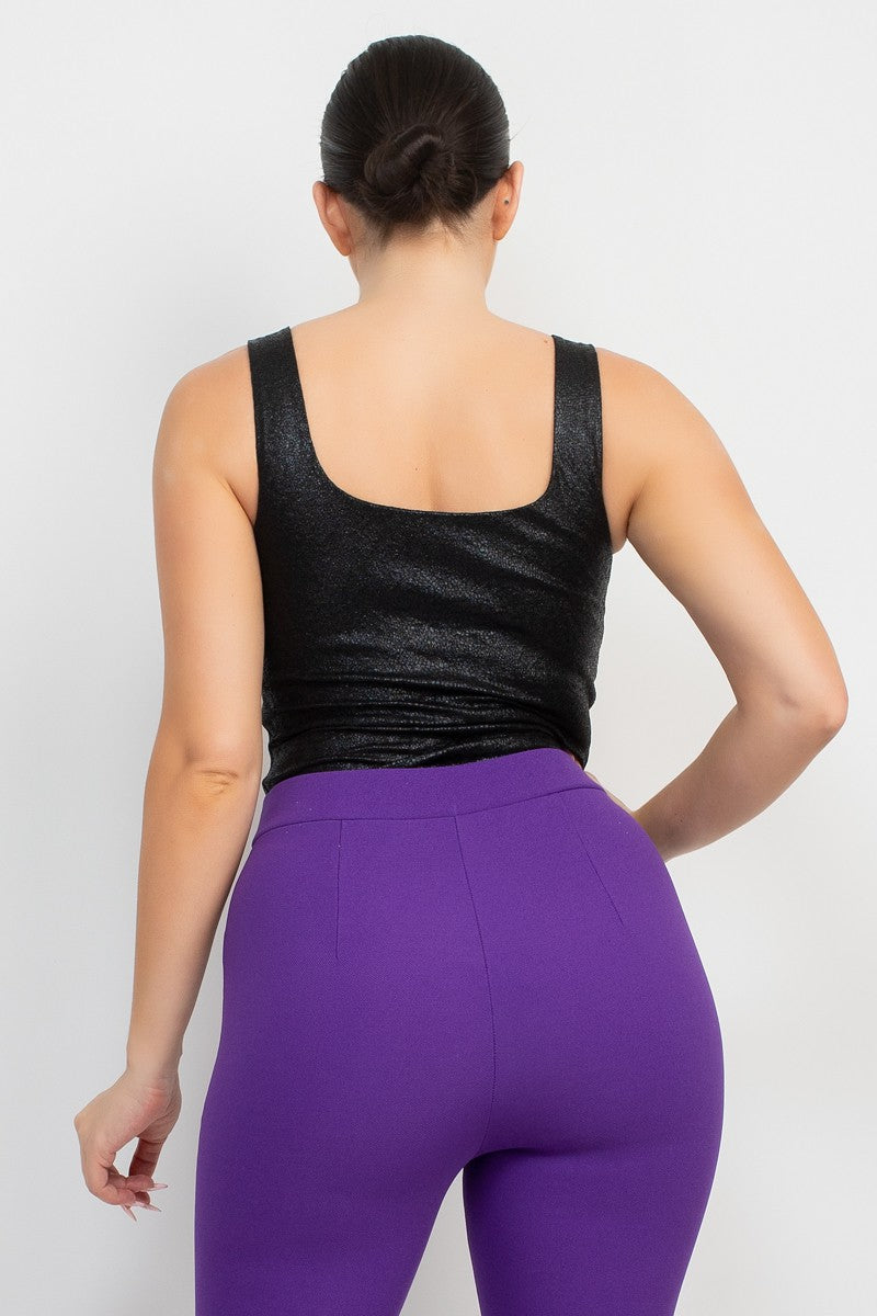 Person wearing a black tank top and purple leggings on a white background