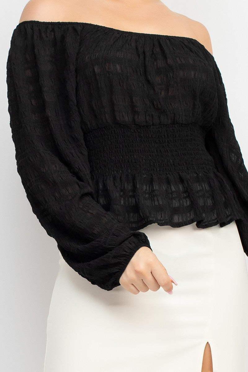 Black off-shoulder top worn by a person on a white background