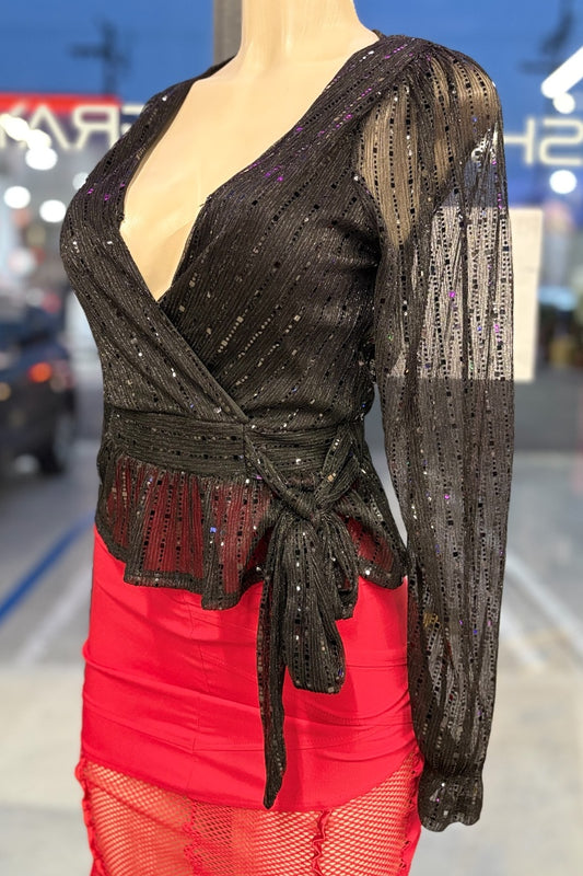 Mannequin wearing a black sequined top and red skirt with a blurred indoor background.