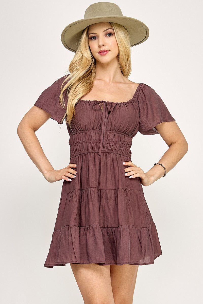 Woman wearing a brown dress and beige hat on a white background