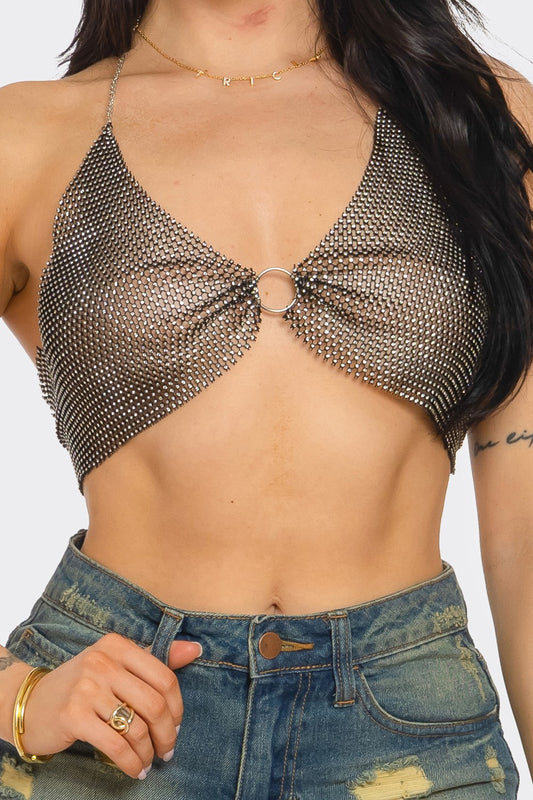 Person wearing a chainmail top and denim shorts on a plain background