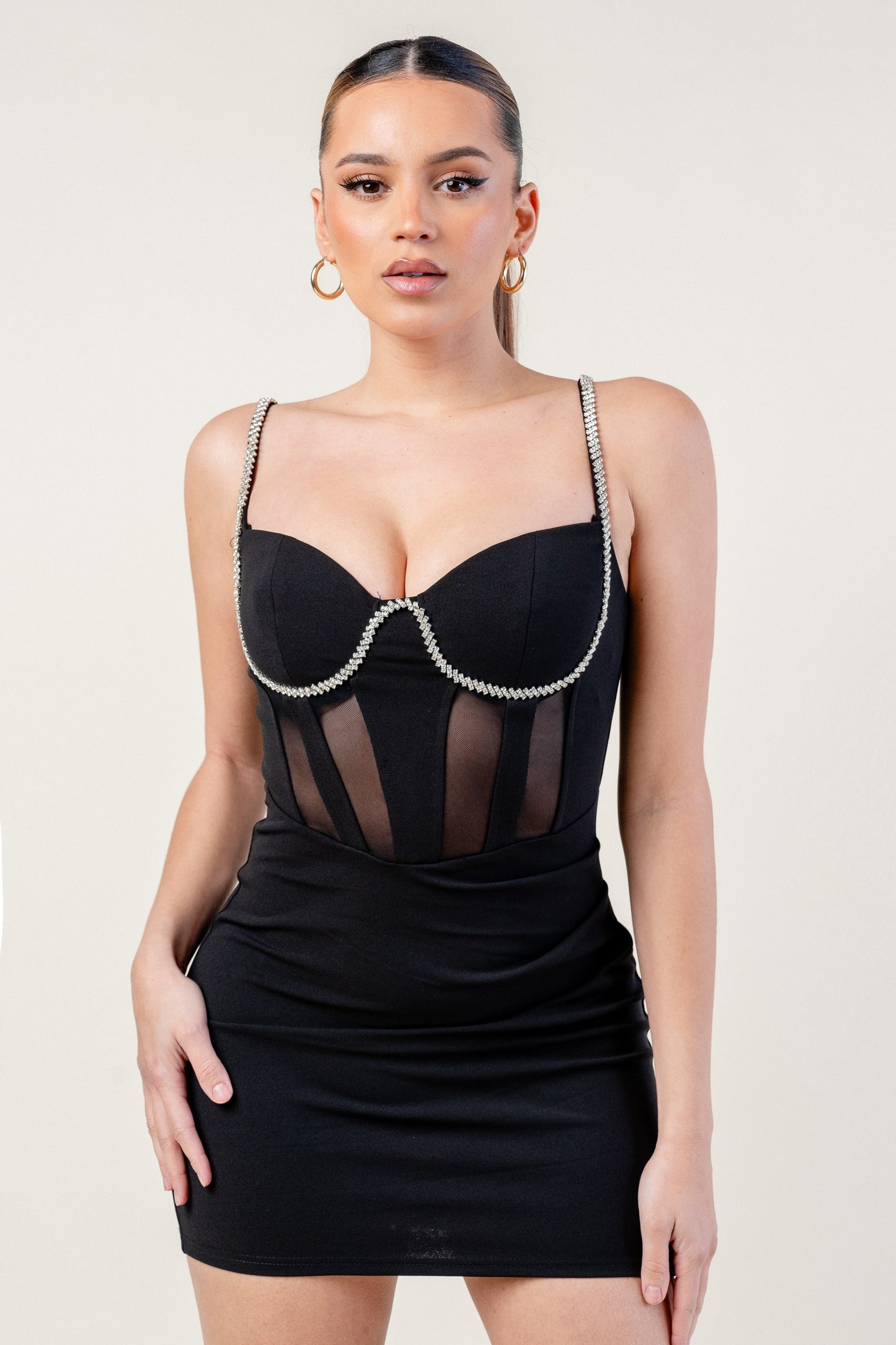 Woman wearing a black dress with sheer details on a white background