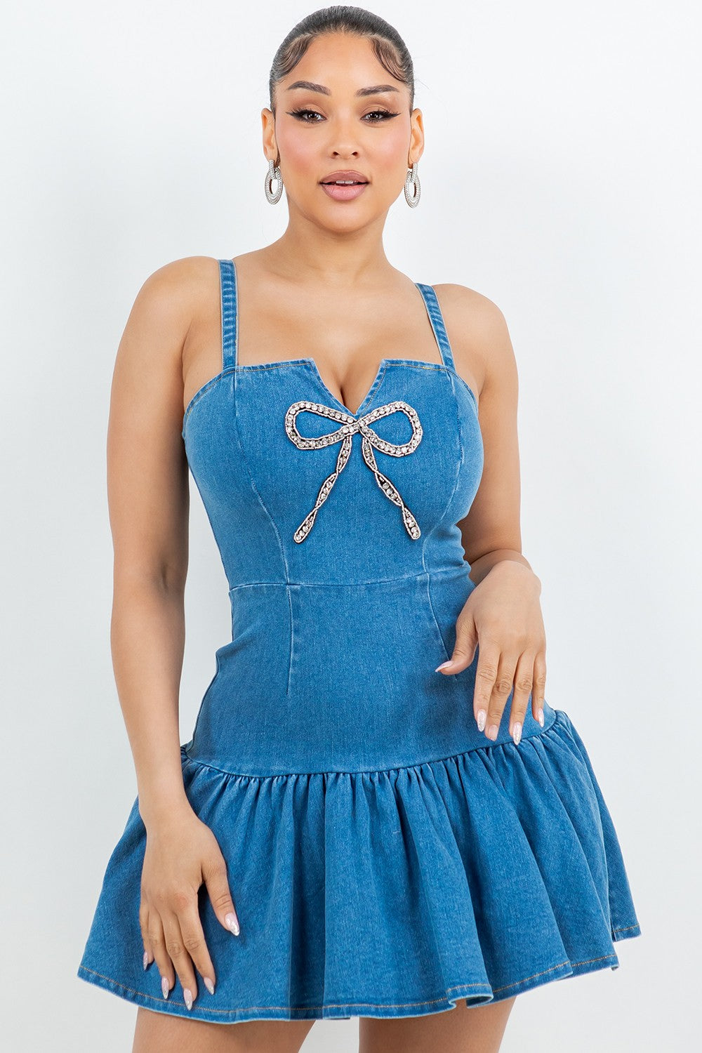 Woman wearing a blue denim dress with a decorative bow on a white background