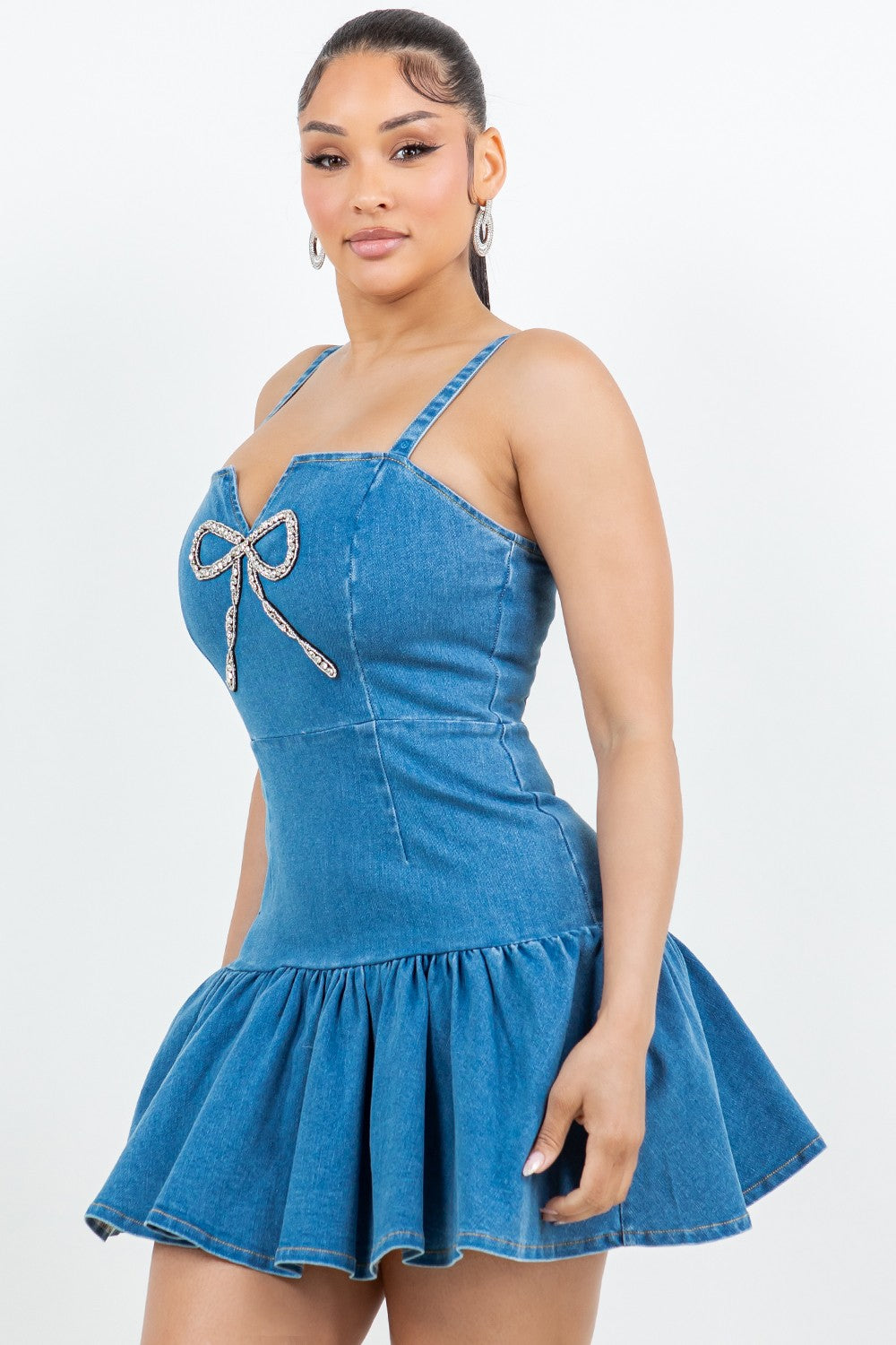 Woman wearing a blue denim dress with a bow detail on a white background