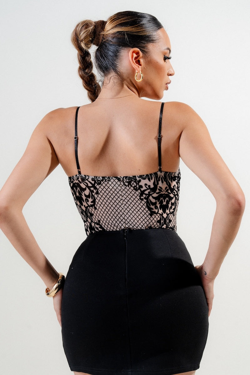 Woman wearing a black and rose print top with a plain background