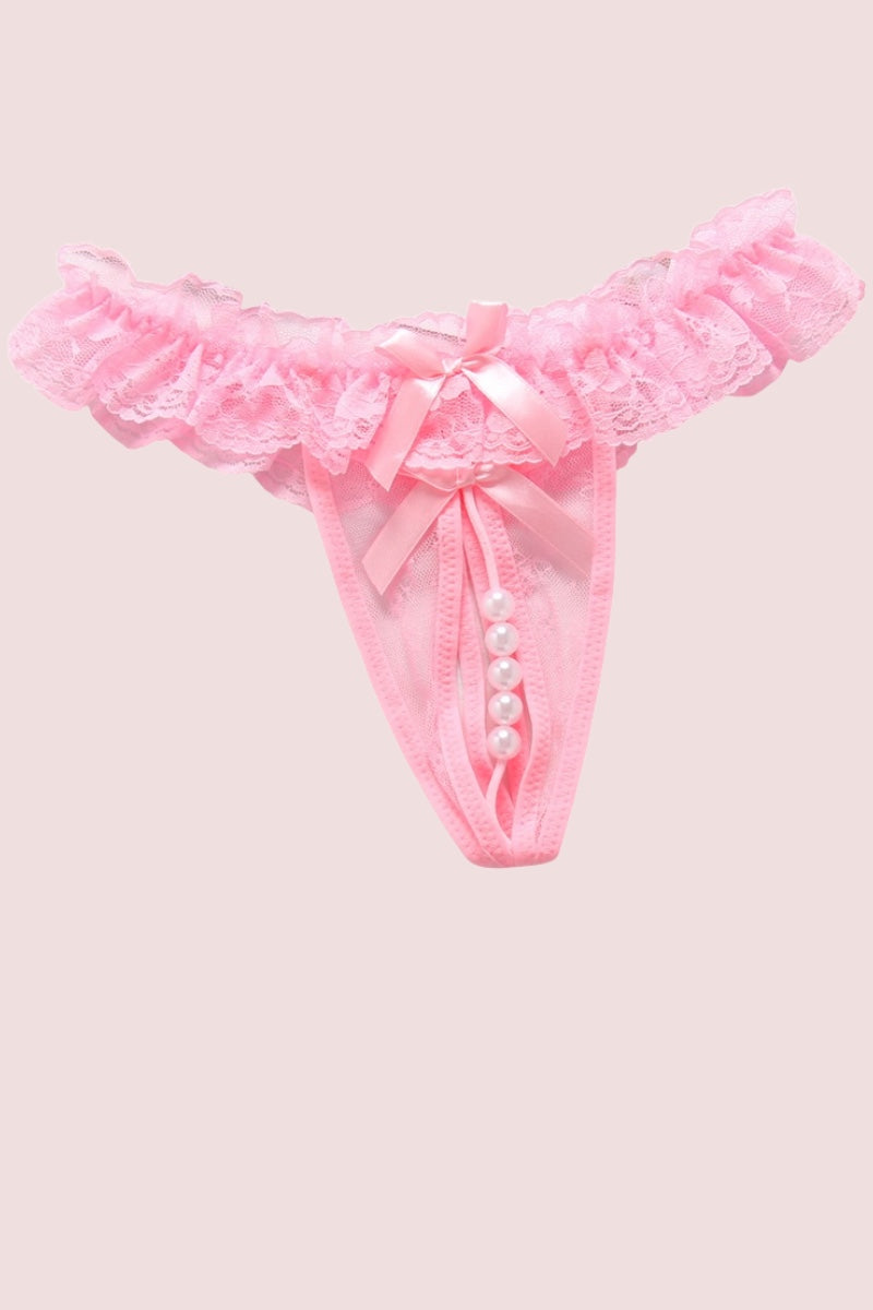 Pink lace thong with a ruffled waistband, satin bow, pearl bead details shown on a solid pale pink background.