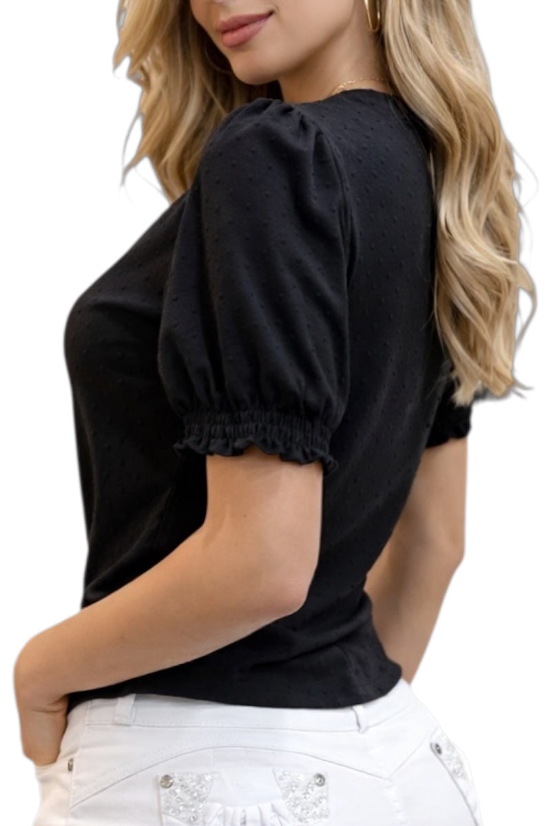 Woman wearing a black top with puff sleeves and white pants on a white background