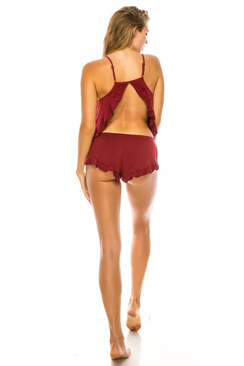 Woman wearing a burgundy set with ruffled details on a white background