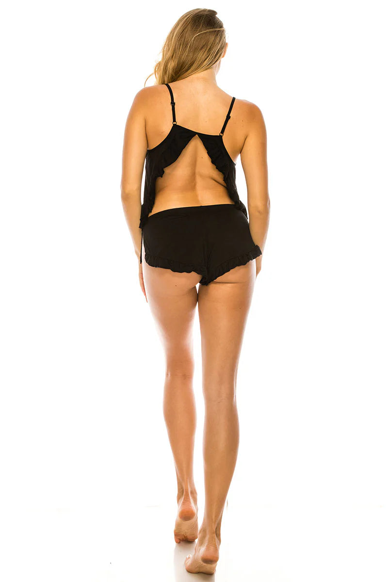 Woman wearing a black strappy top and shorts on a white background