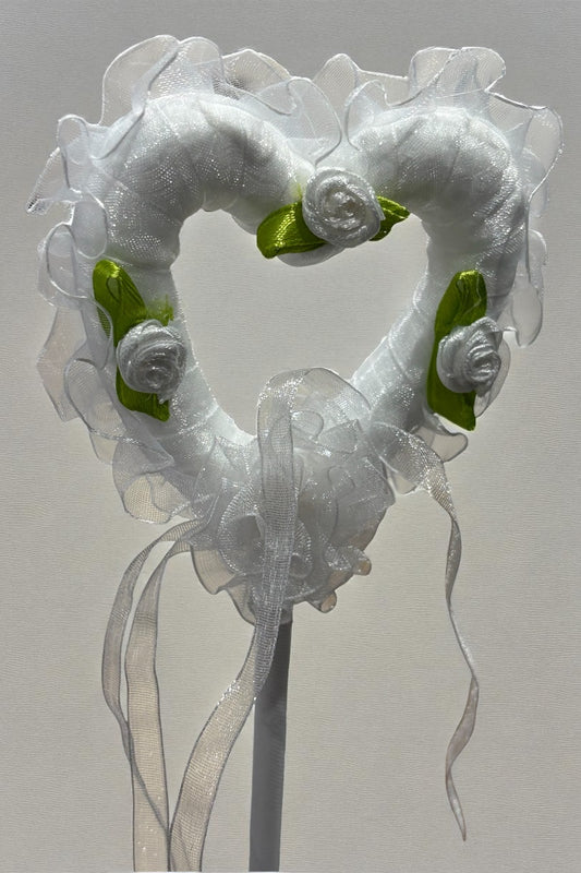 Decorative heart-shaped object with ribbons and flowers on a gray background