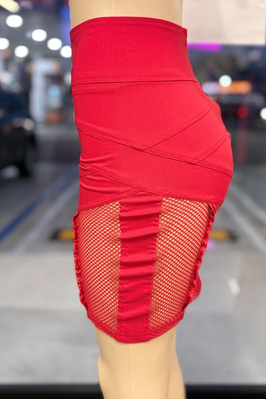 Red skirt with fishnet panels worn by a person, blurred indoor background
