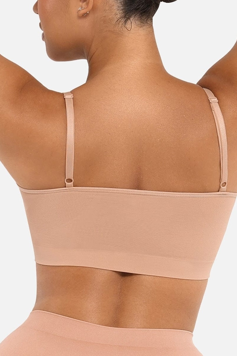 Woman wearing a beige bralette on a white background