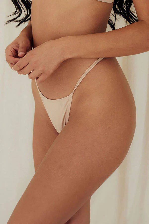 Beige thong bottom worn by a person on a plain background
