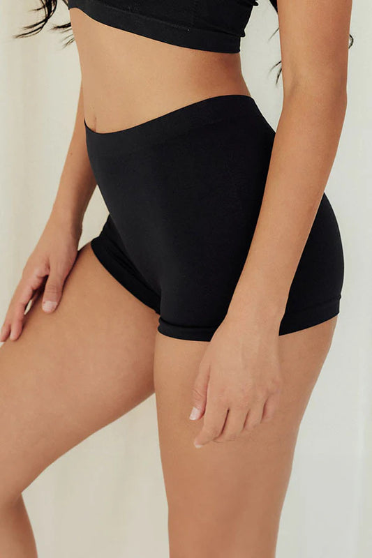 Person wearing black high-waisted shorts on a plain background