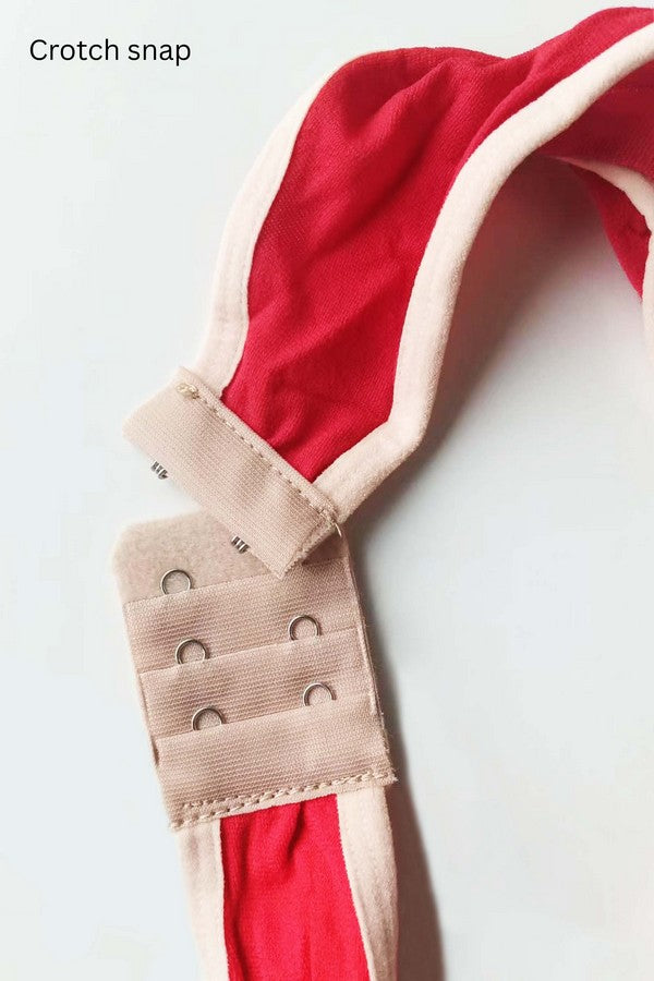 Close-up of a crotch snap on red fabric with a beige strap.