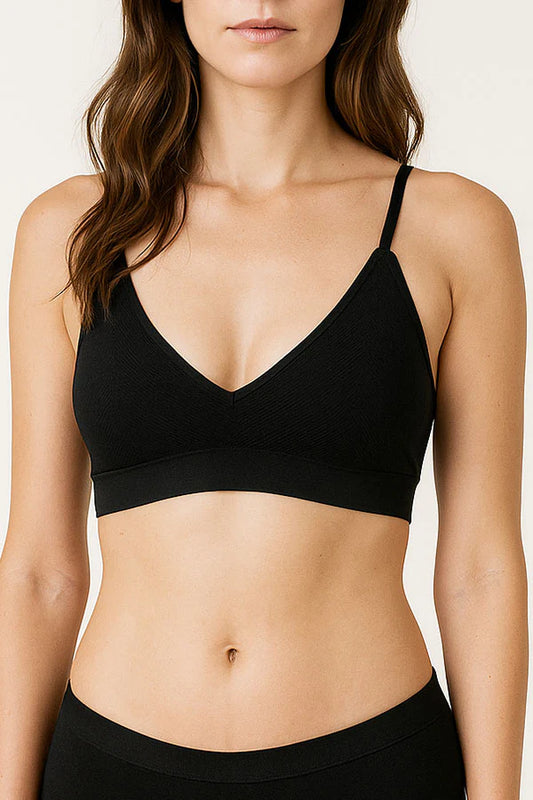 Woman wearing a black bra against a plain background