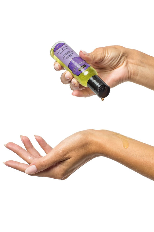 Hand holding a bottle of green liquid with a purple label against a white background