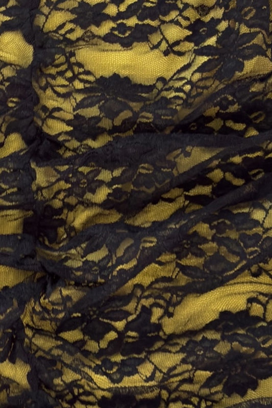 Close-up of black lace fabric with a yellow background