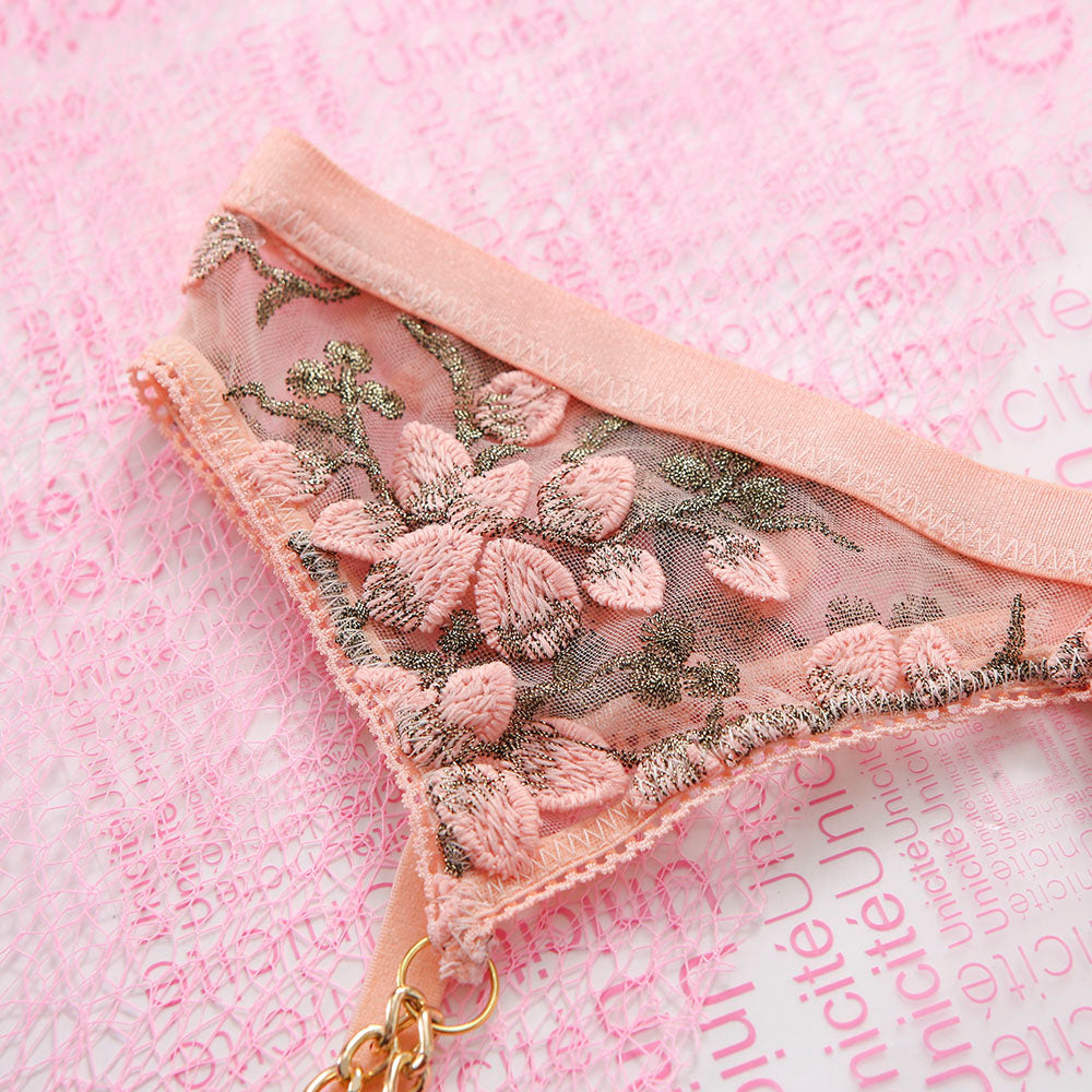 Pink lace garter belt with floral embroidery on a pink background