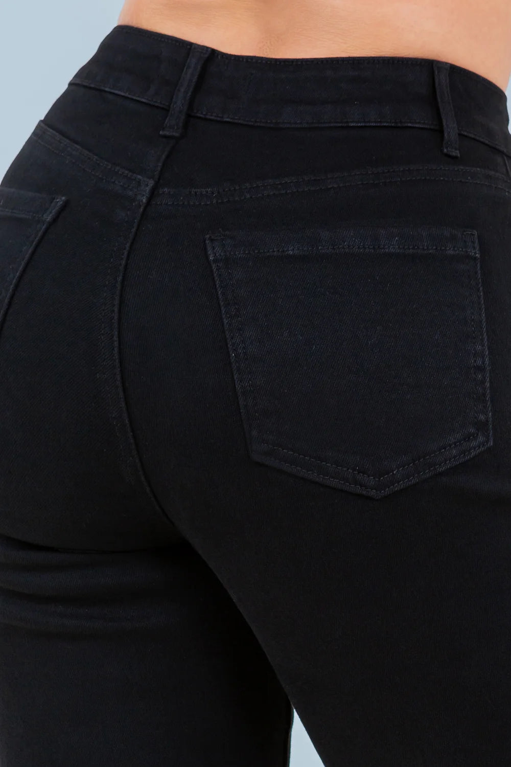Close-up of black pants with a pocket detail on a light blue background