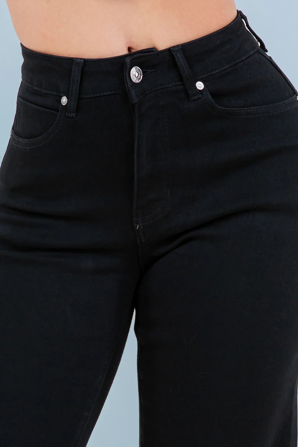 Black jeans worn by a person on a light blue background