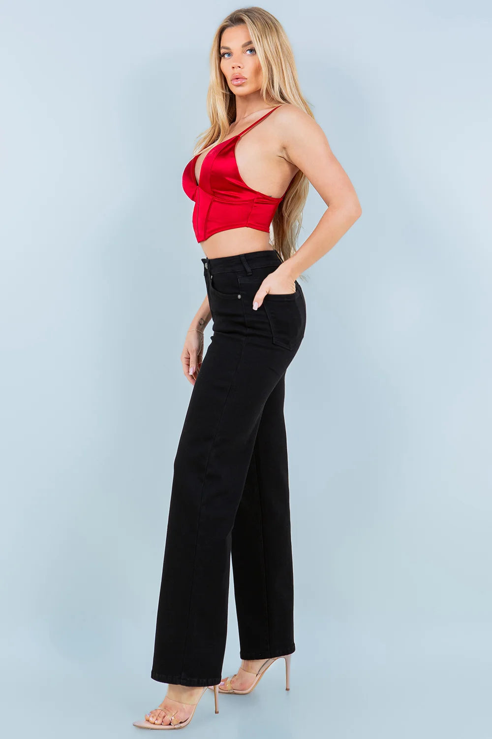 Woman wearing a red top and black pants against a light blue background