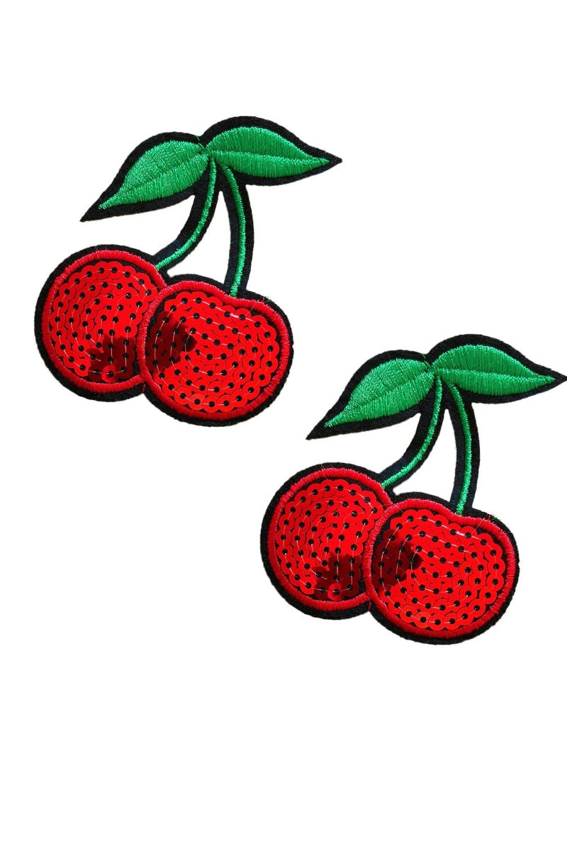 Two red cherry pasties with green leaves on a white background