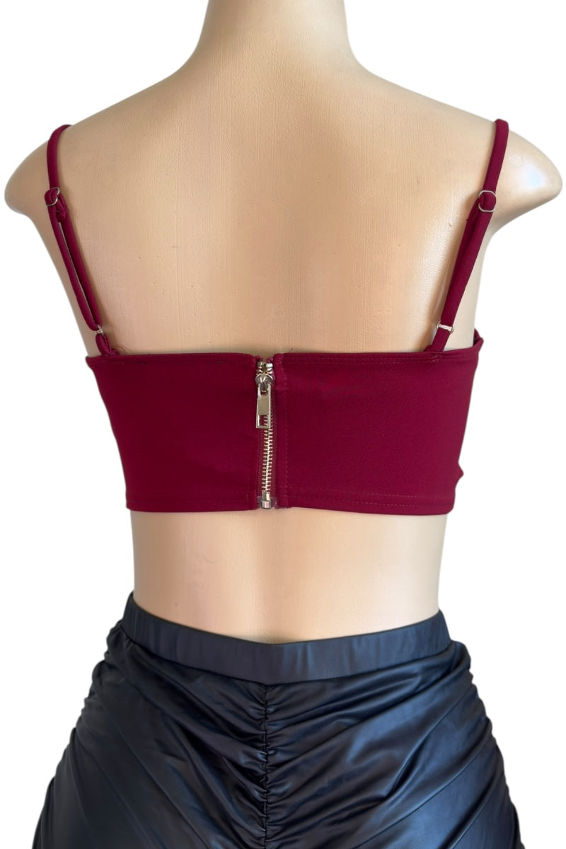 burgundy crop top with thin straps and zipper on a mannequin against a white background