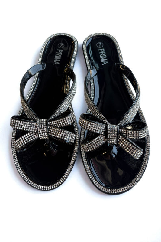 Black sandals with rhinestone bow design on a white background