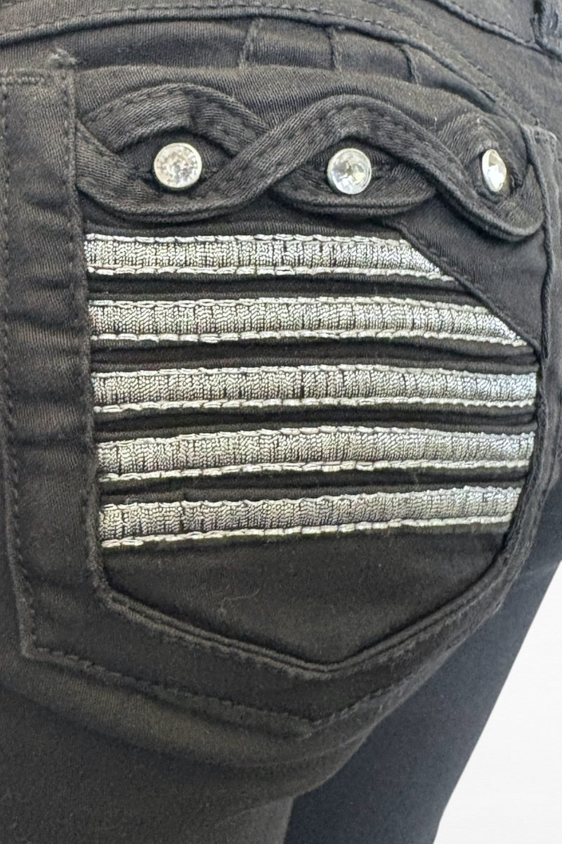 Close-up of a black pocket with decorative stitching and buttons on a garment.
