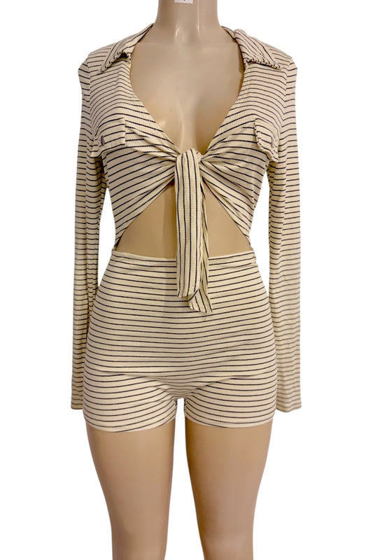 A cream and black striped two-piece style romper consisting of a long-sleeve crop top with a front tie detail and matching high-waisted shorts, displayed on a mannequin against a white background.