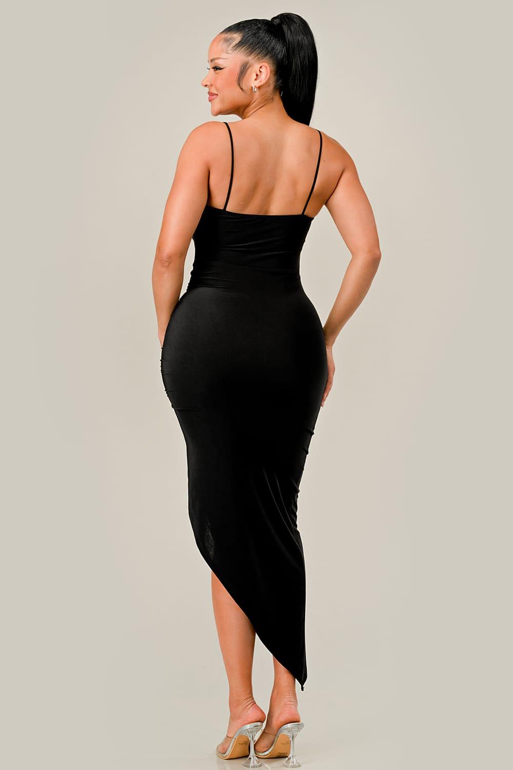 Woman wearing a black dress with thin straps on a plain background