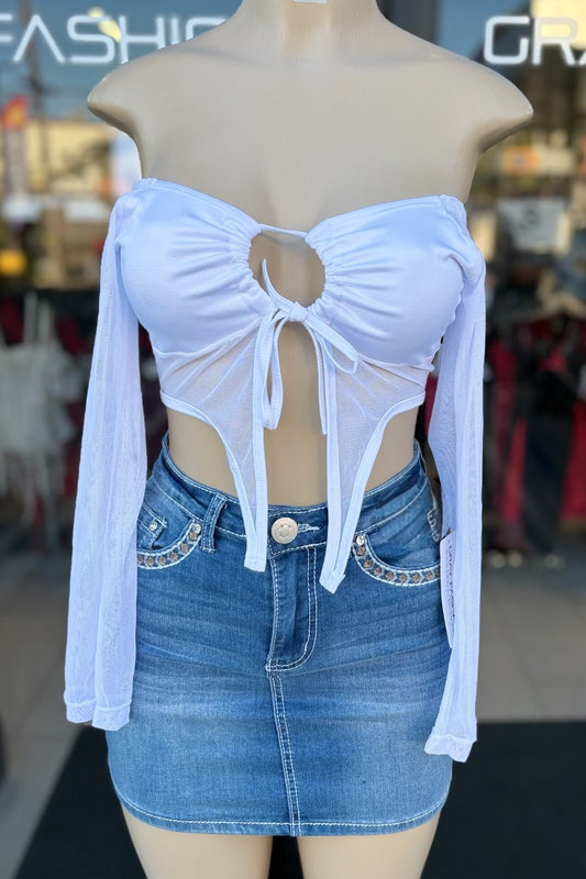Mannequin wearing a white crop top with cut-out design and a denim skirt in a store setting.