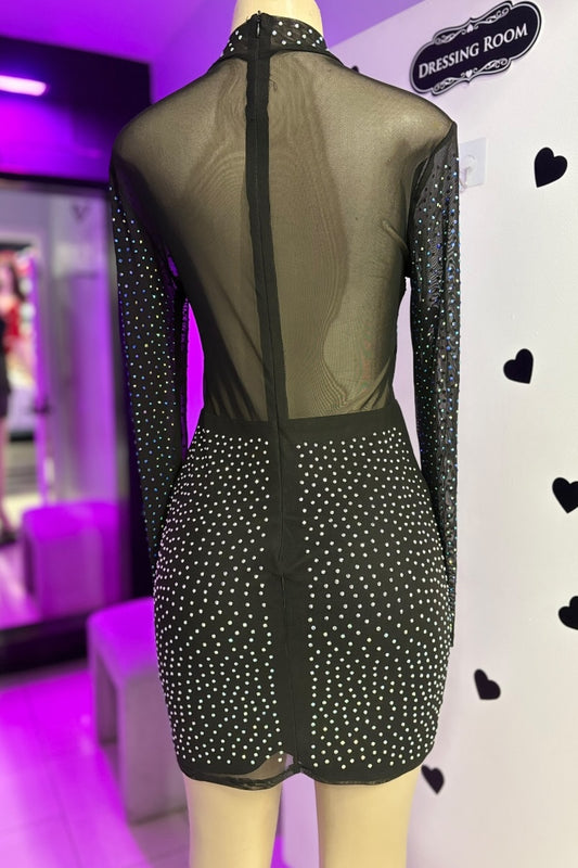 Mannequin wearing a black dress with sheer overlay in a dressing room setting.