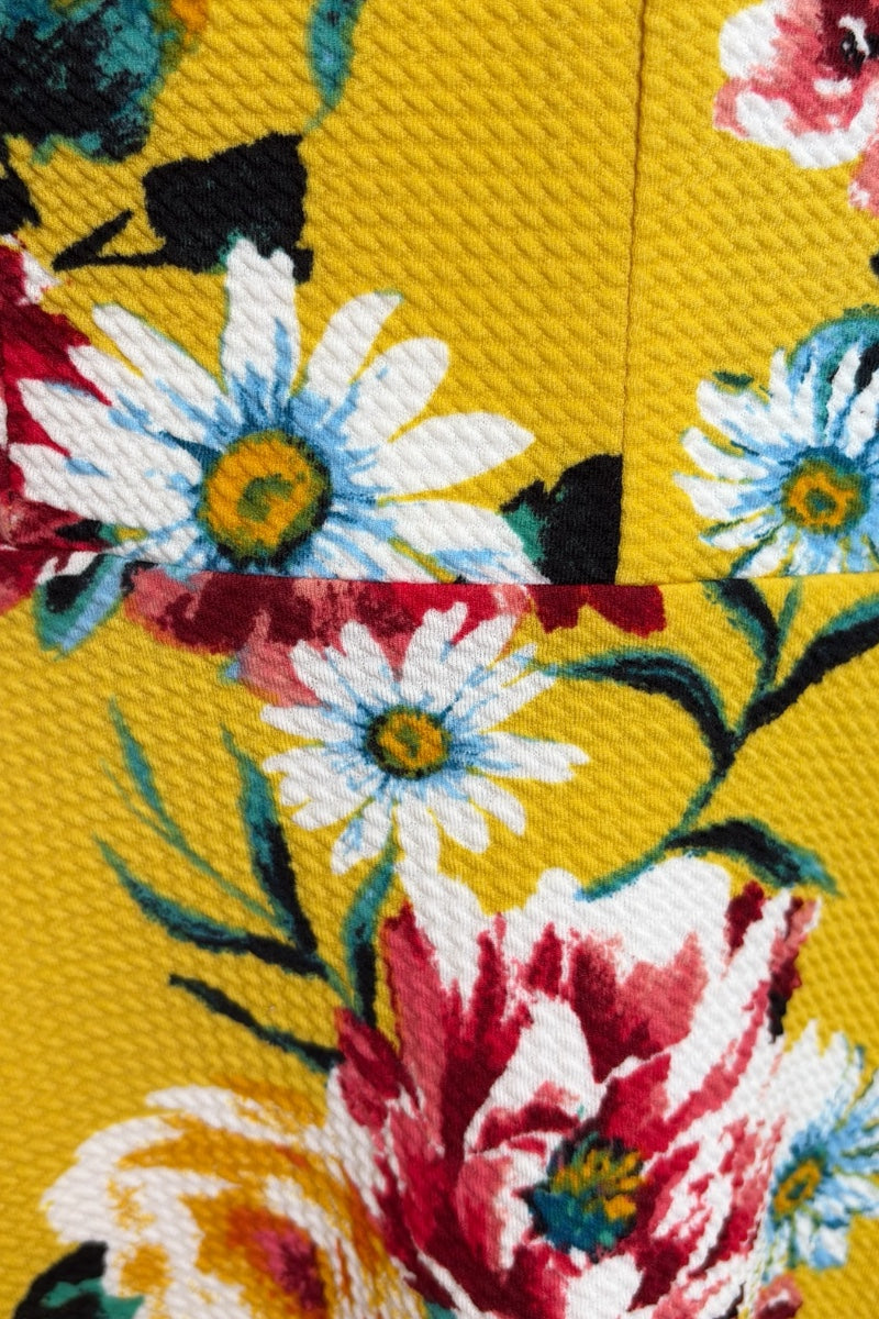 Close-up of a fabric with colorful florals on a yellow background