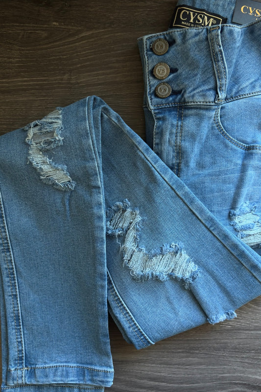 Distressed blue jeans with visible brand label on a wooden surface