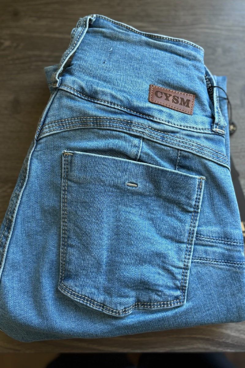 Folded blue jeans with a visible brand label on a wooden surface