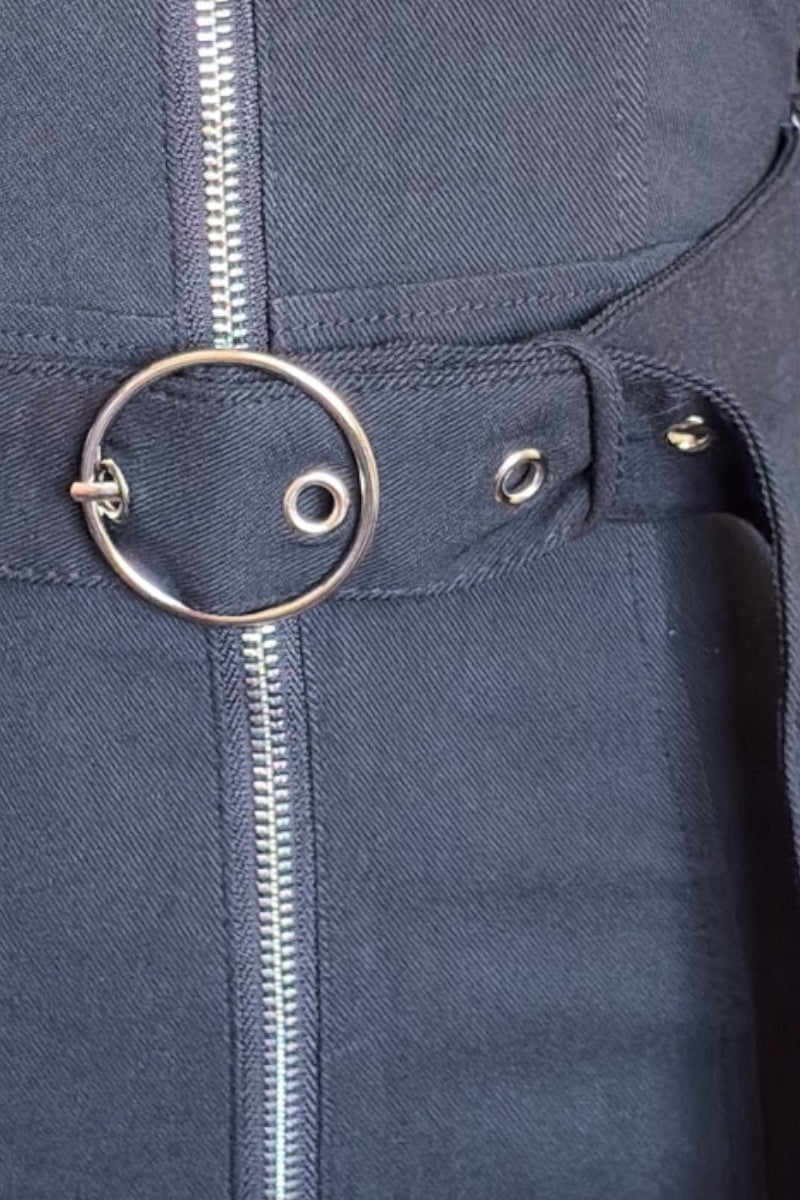 Close-up of a black dress with a zipper and circular metal detail.