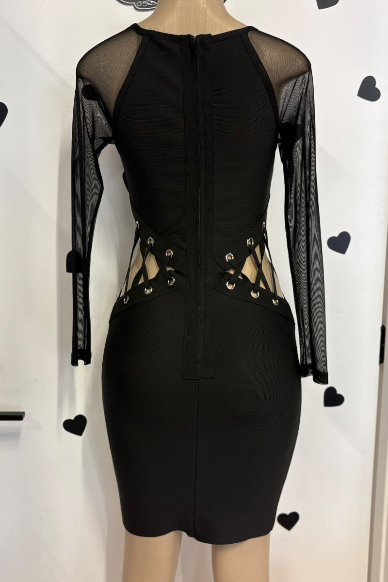 Black dress with sheer sleeves and lace-up front on a mannequin against a white background.