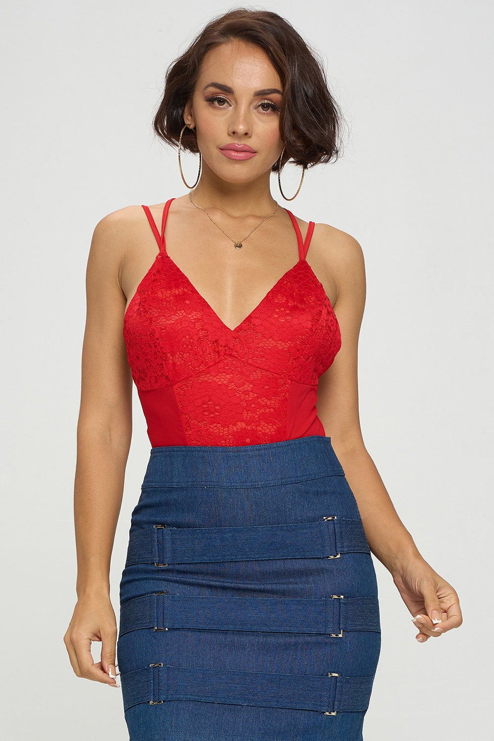 Woman wearing a red lace top and blue denim skirt on a white background
