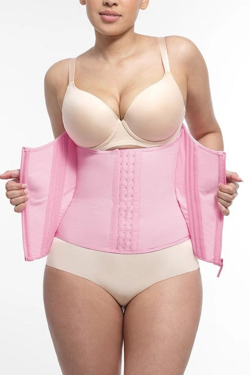 Woman wearing a pink waist trainer with beige bra and underwear on a white background